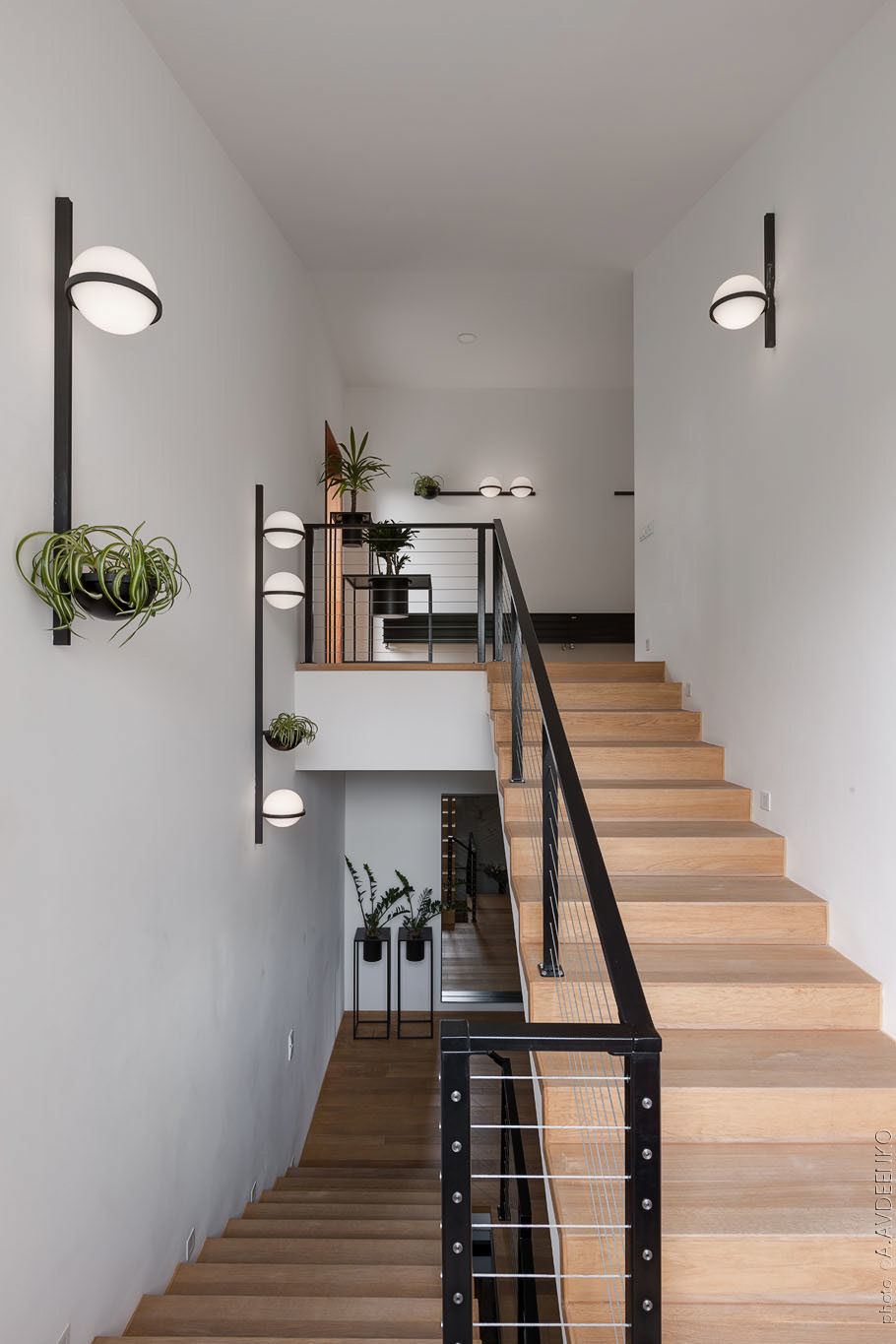 Cầu thang bằng gỗ với tay vịn kim loại sơn đen dẫn lối lên tầng trên