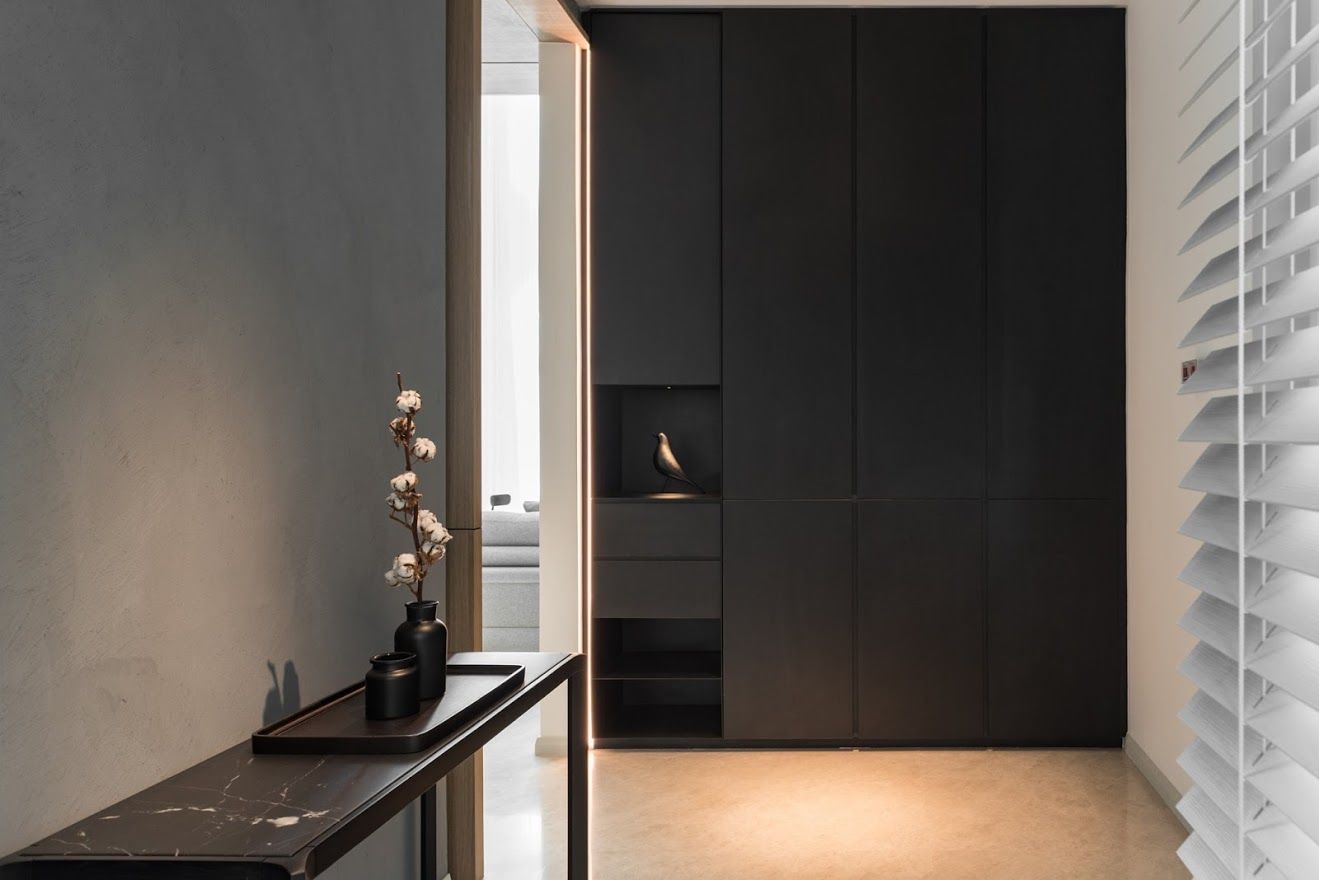 Một góc hành lang đặt tủ âm tường đen và một chiếc bàn nhỏ để đồ trang trí